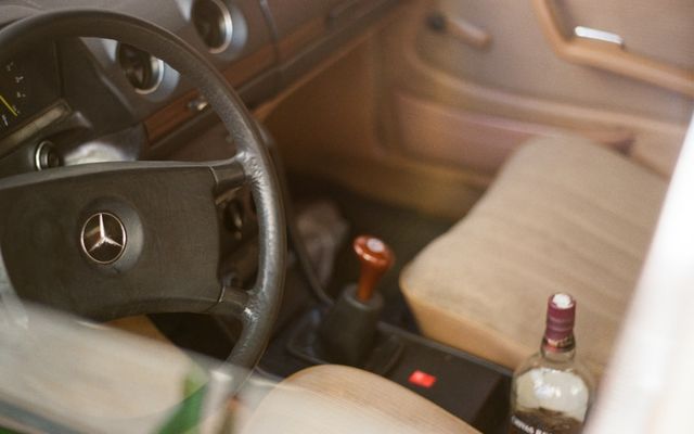 a bottle of alcohol sitting in the driver's seat of a car