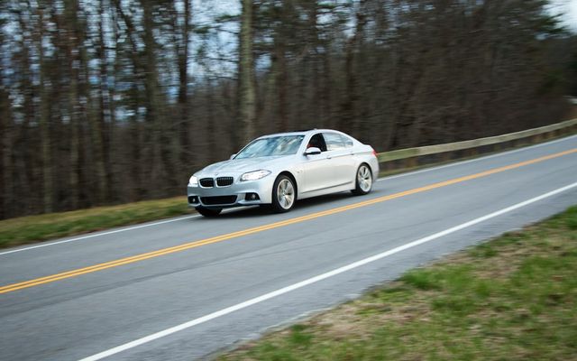 Silver sedan driving on a rural road.
