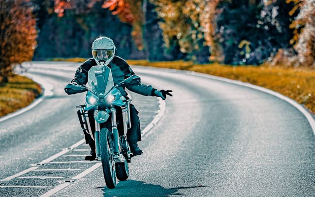 Motorcyclist riding on a winding road in autumn.
