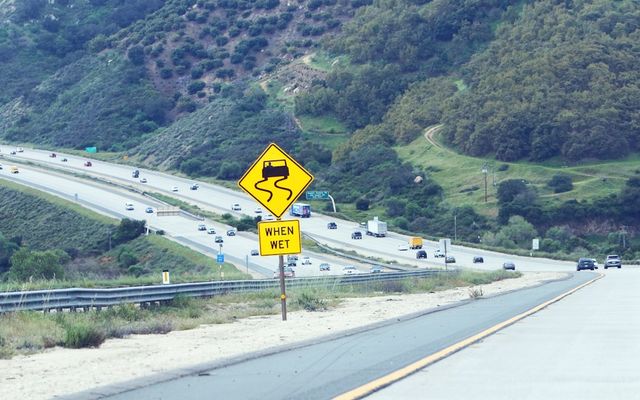 Slippery when wet road sign on highway