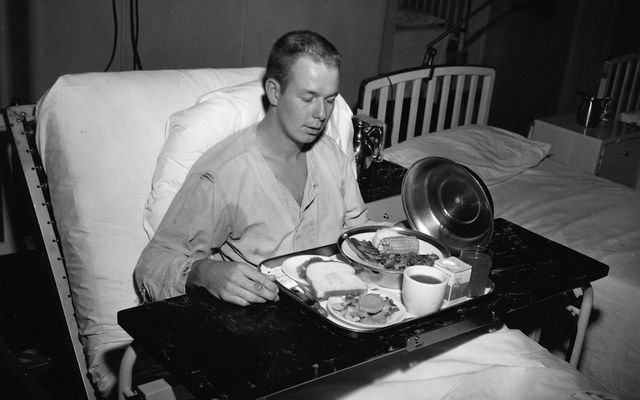 A man in a hospital bed eating a meal