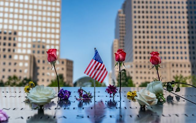 Flowers are placed on a memorial in front of tall buildings