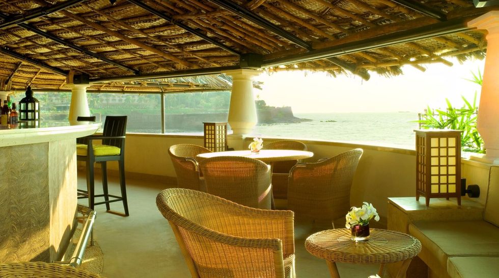 Open air seaside bar with simple chairs, sunlight, and calm sea