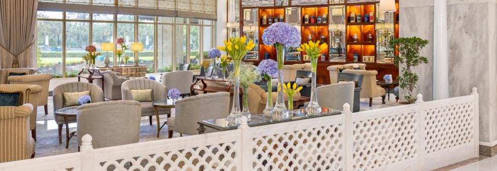 Luxury hotel lounge interior with plush seating, floral décor, and garden views
