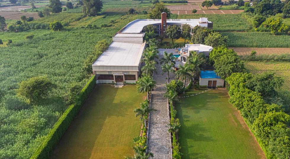 Aerial top view of Ginger Agra, Bichpuri property surrounded by green palm trees and lush greenery.