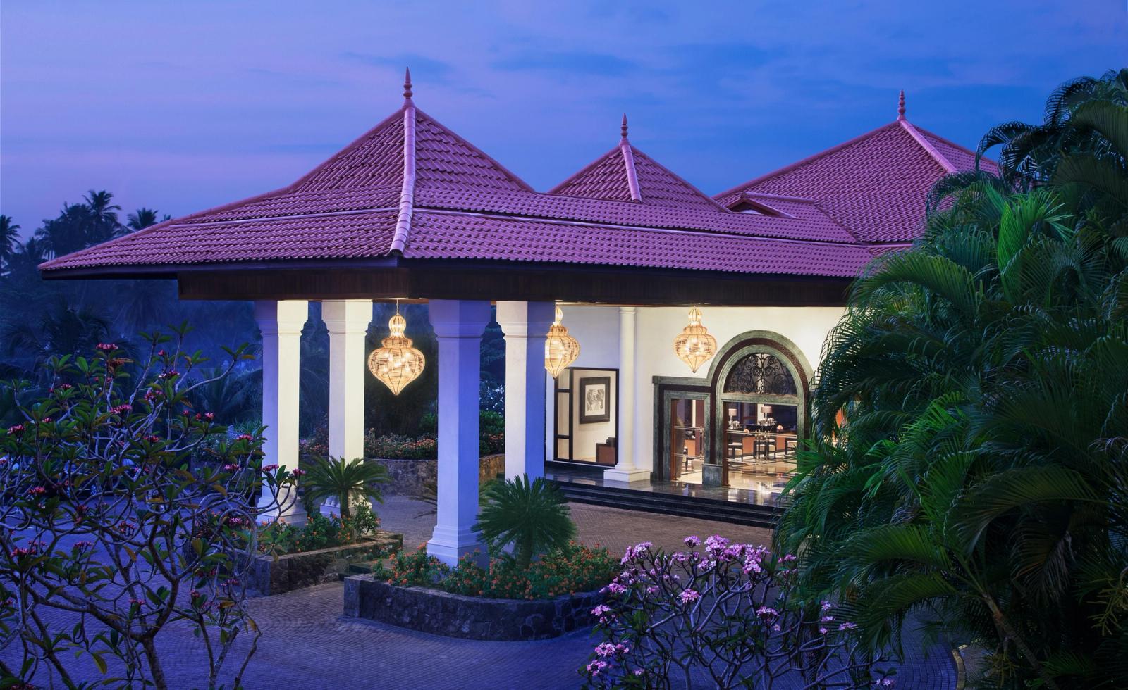 The lobby pavilion lit at dusk, with tiled roofs, white columns and frangipani around it.