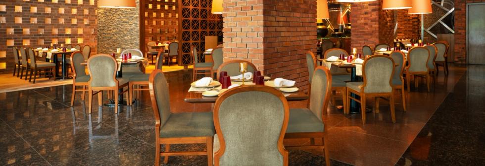 Hotel restaurant with brick walls, wooden chairs, and set dining tables