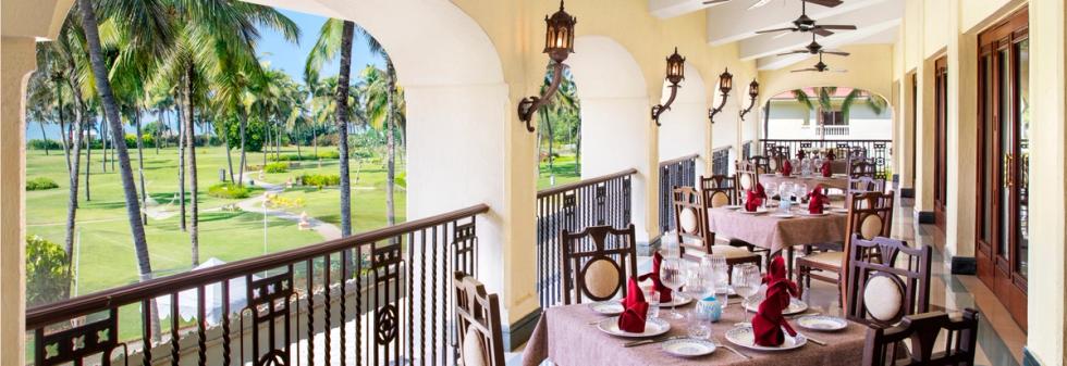 Open-air restaurant balcony overlooking palm trees and lawns