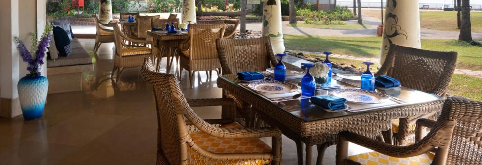 Garden facing restaurant with woven chairs, blue tableware, and natural light