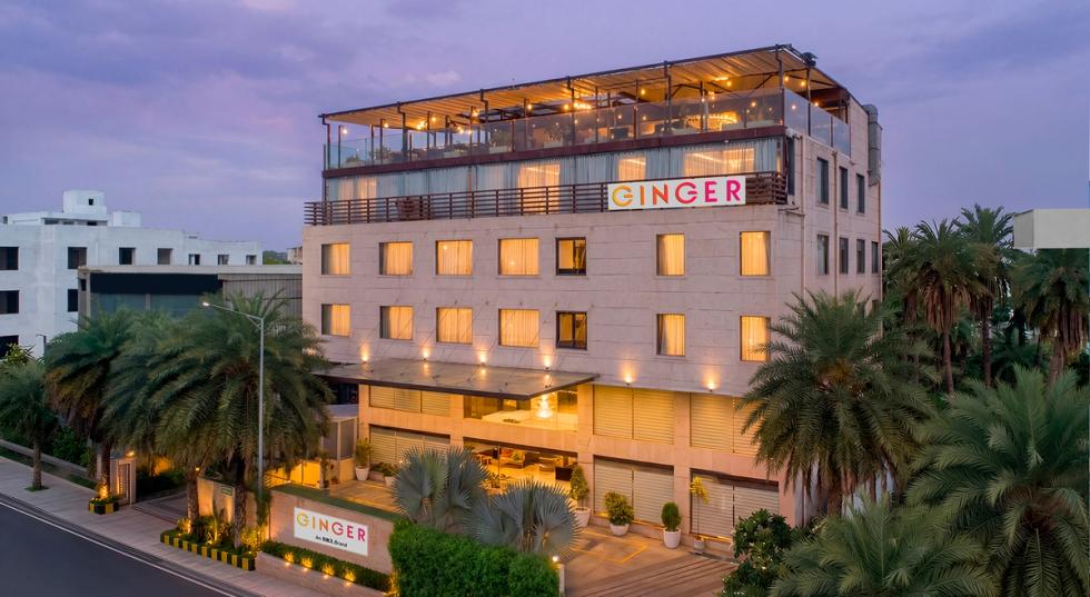 Exterior view of Ginger Bhopal, Shahpura Lake hotel with a rooftop restaurant at twilight.