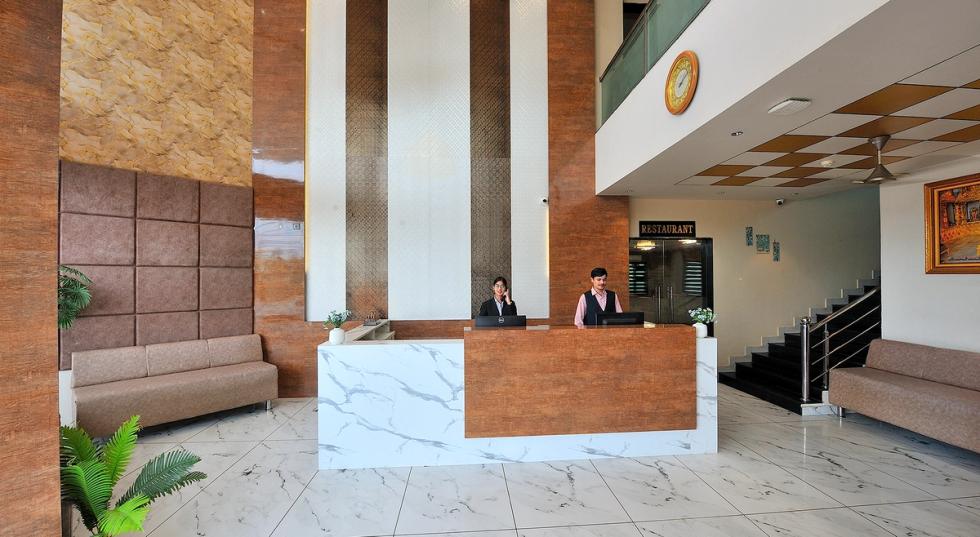 Hotel lobby with front desk and guest seating at Ginger Somnath.