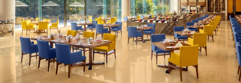 Bright restaurant interior featuring blue and yellow chairs and wooden tables