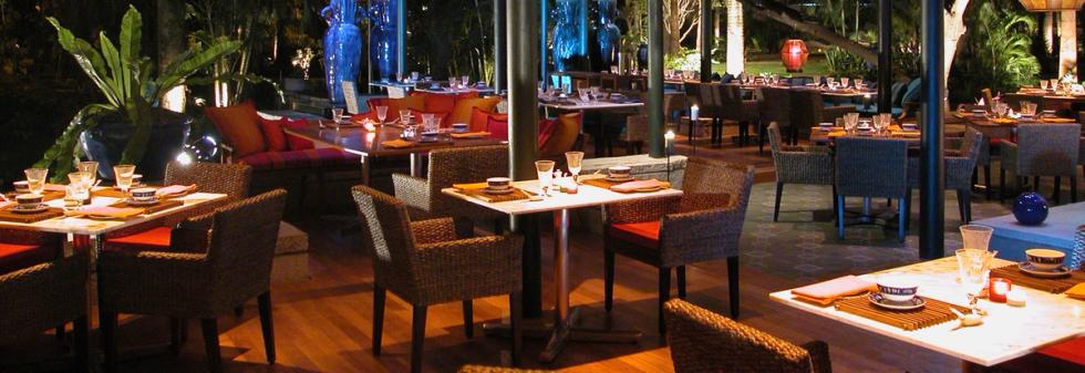 Open-air luxury restaurant with table settings and warm ambient lighting