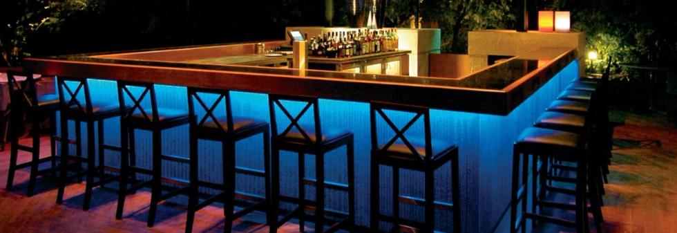 Luxury open-air bar featuring a wooden counter and illuminated bar front.