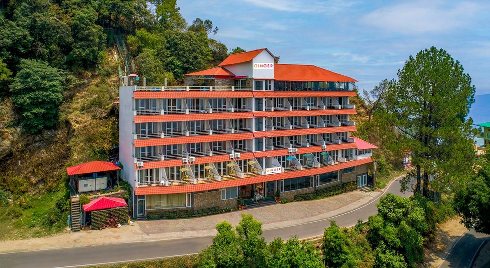 Exterior view of Ginger Lansdowne hotel on Mall Road surrounded by green hills.