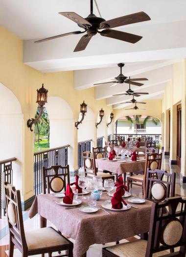 Open-air restaurant balcony overlooking palm trees and lawns