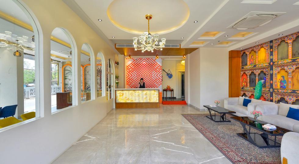 Luxury lobby and reception area of Ginger Kota, Vishwakarma Nagar hotel featuring modern chandeliers, vibrant Rajasthani wall art, and elegant marble flooring.