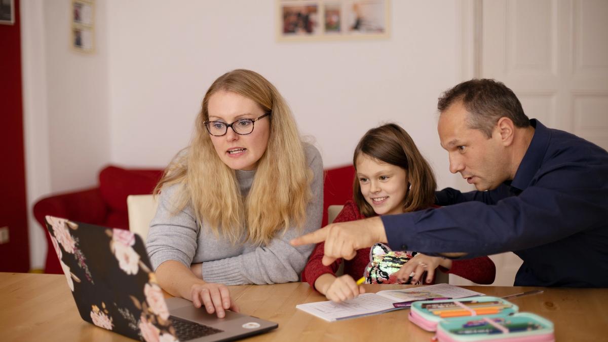 Mom and dad helping daughter with online class