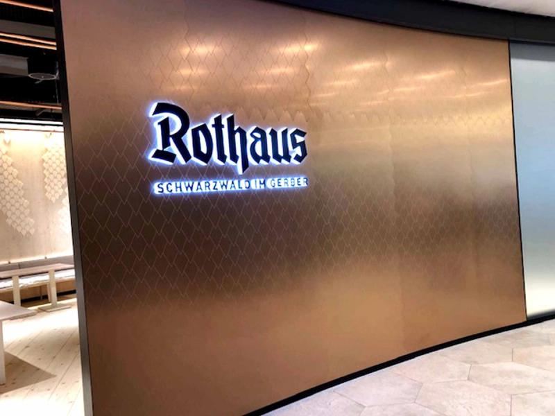 Strefa wejściowa do restauracji Rothaus im Gerber z podświetlanym napisem na powierzchni mirrorINOX