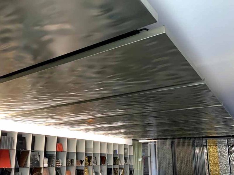 Faliste srebrne metalowe panele sufitowe nad regałem z materiałami