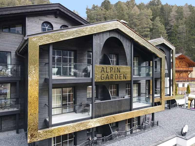 Fasada Alpin Garden Hotel ze złotym obramowaniem i balkonami