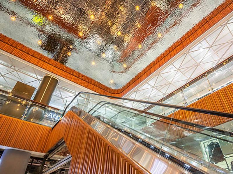 Schody ruchome jadące w górę pod lśniącym metalowym sufitem w centrum handlowym
