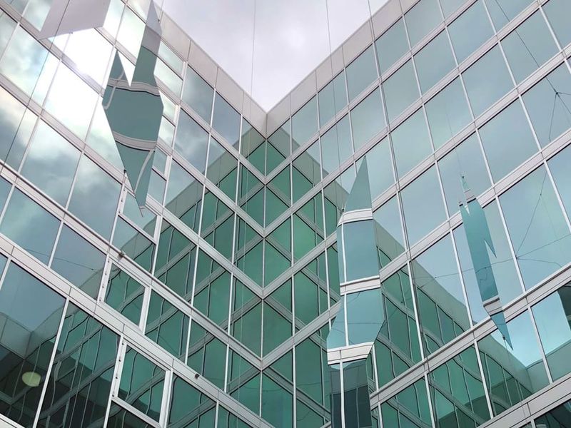 Widok szczegółowy refleksyjnych powierzchni lustrzanych na tle szklanej fasady