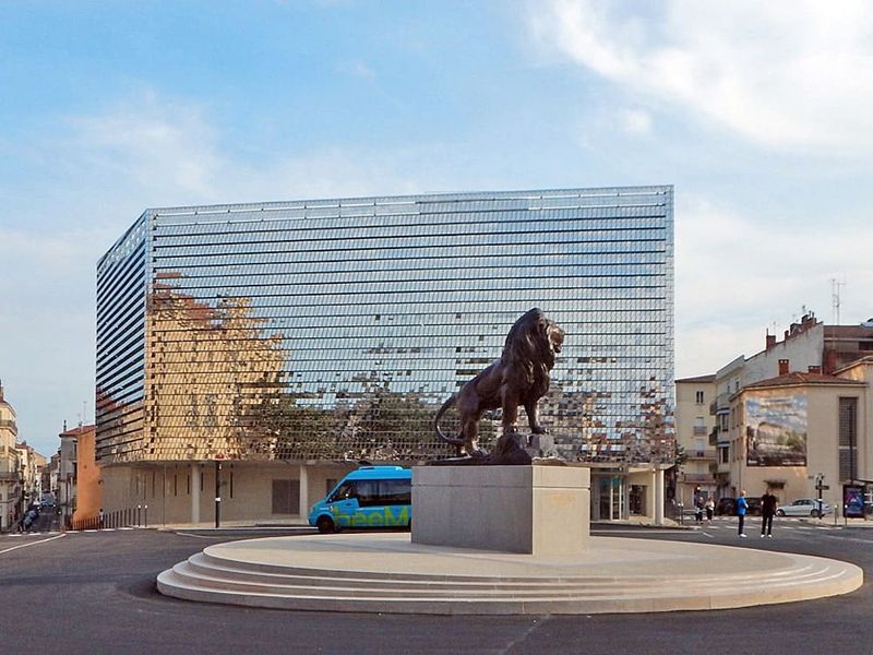 Parking Charles de Gaulle z lustrzaną elewacją za posągiem lwa