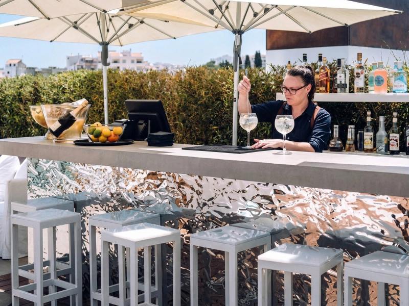 Zbliżenie na barmankę przygotowującą koktajl w barze na tarasie dachowym w Lagos, przy ladzie z wykończeniem powierzchni firmy mirrorINOX
