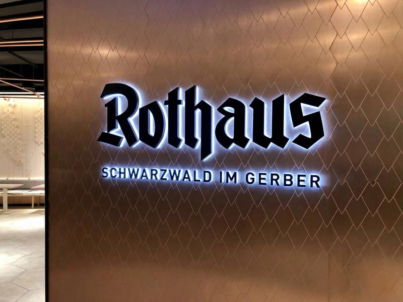 Strefa wejściowa do restauracji Rothaus im Gerber z podświetlanym napisem na powierzchni mirrorINOX