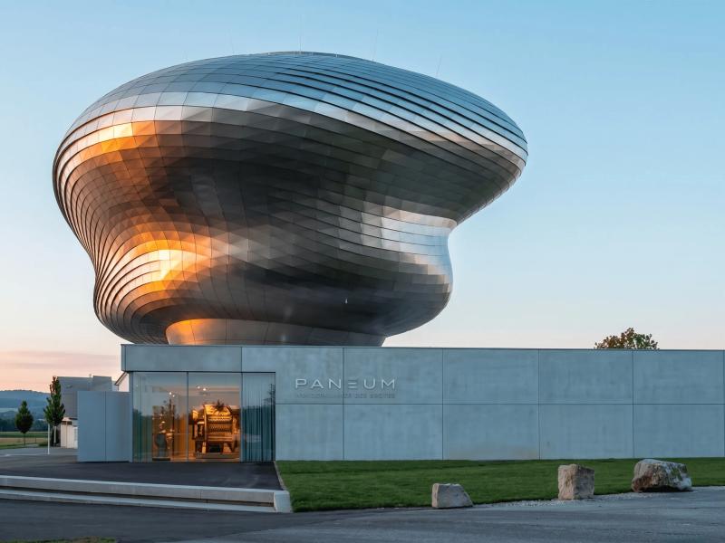 Nowoczesny budynek architektoniczny Paneum z metalicznie połyskującą, zakrzywioną fasadą