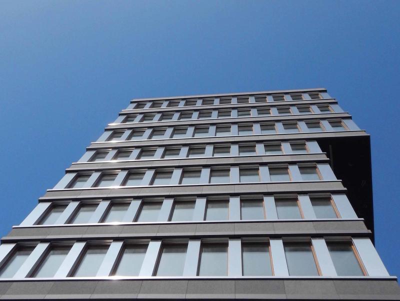 Widok od dołu na wielokondygnacyjny budynek z przesuniętą strukturą elewacji