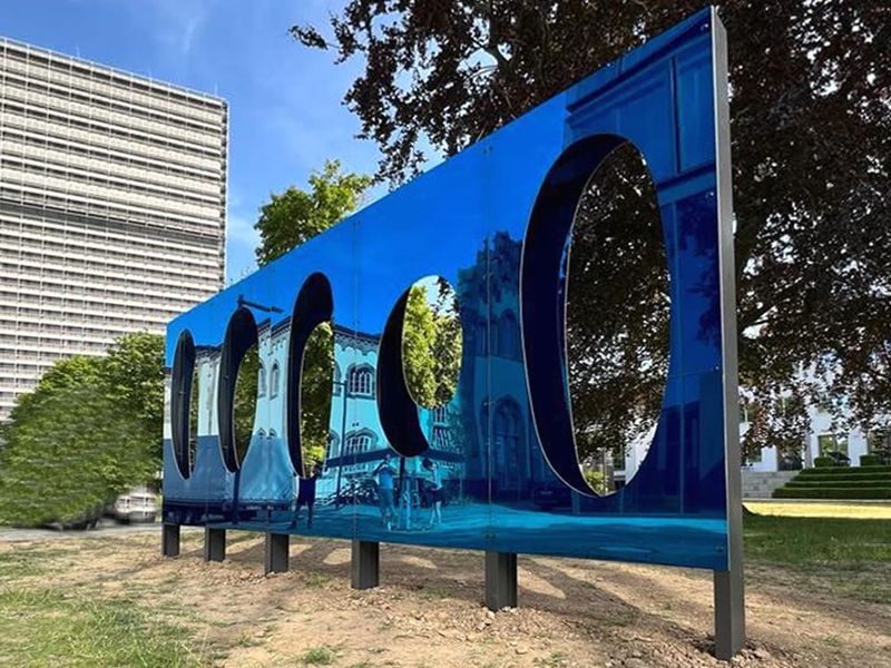 Widok perspektywiczny niebieskiej rzeźby Imagine na tle nowoczesnej architektury