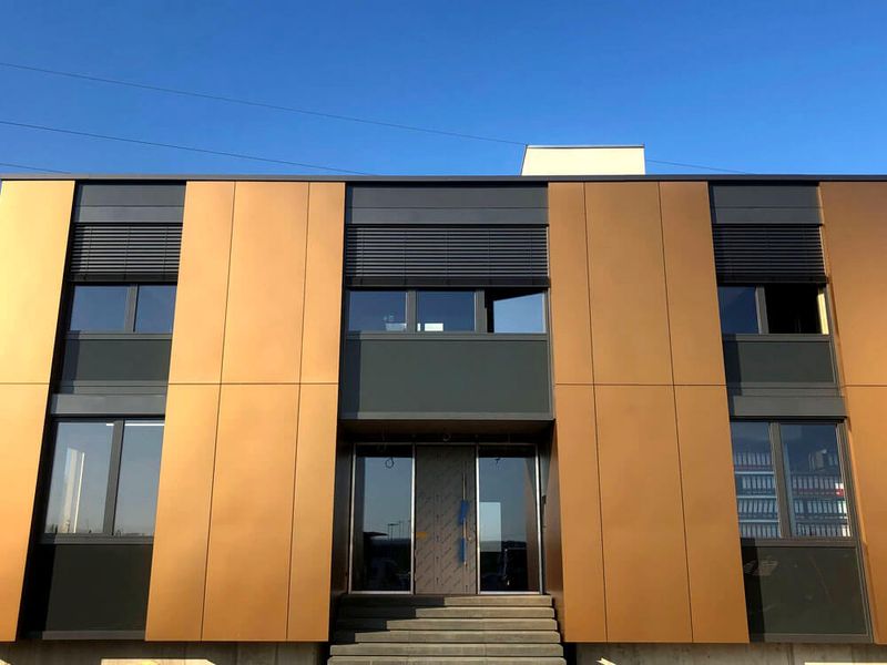 Widok od frontu na miedzianą elewację budynku ze zintegrowanymi żaluzjami