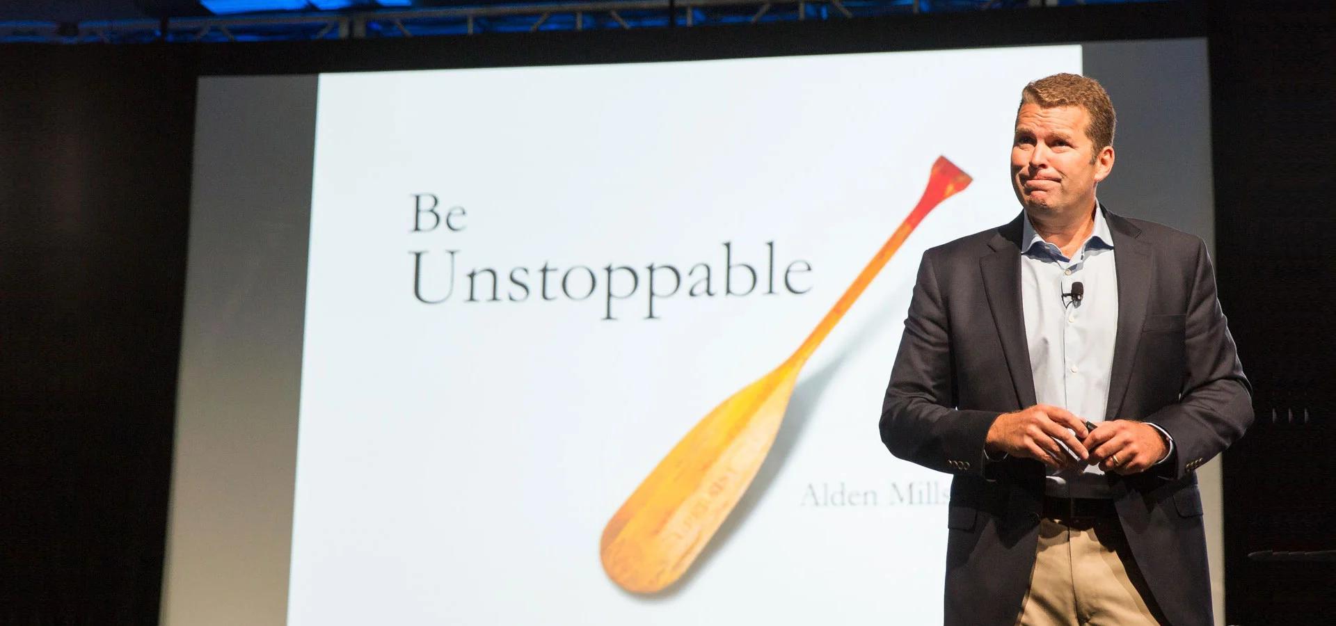 Alden Mills speaking on stage