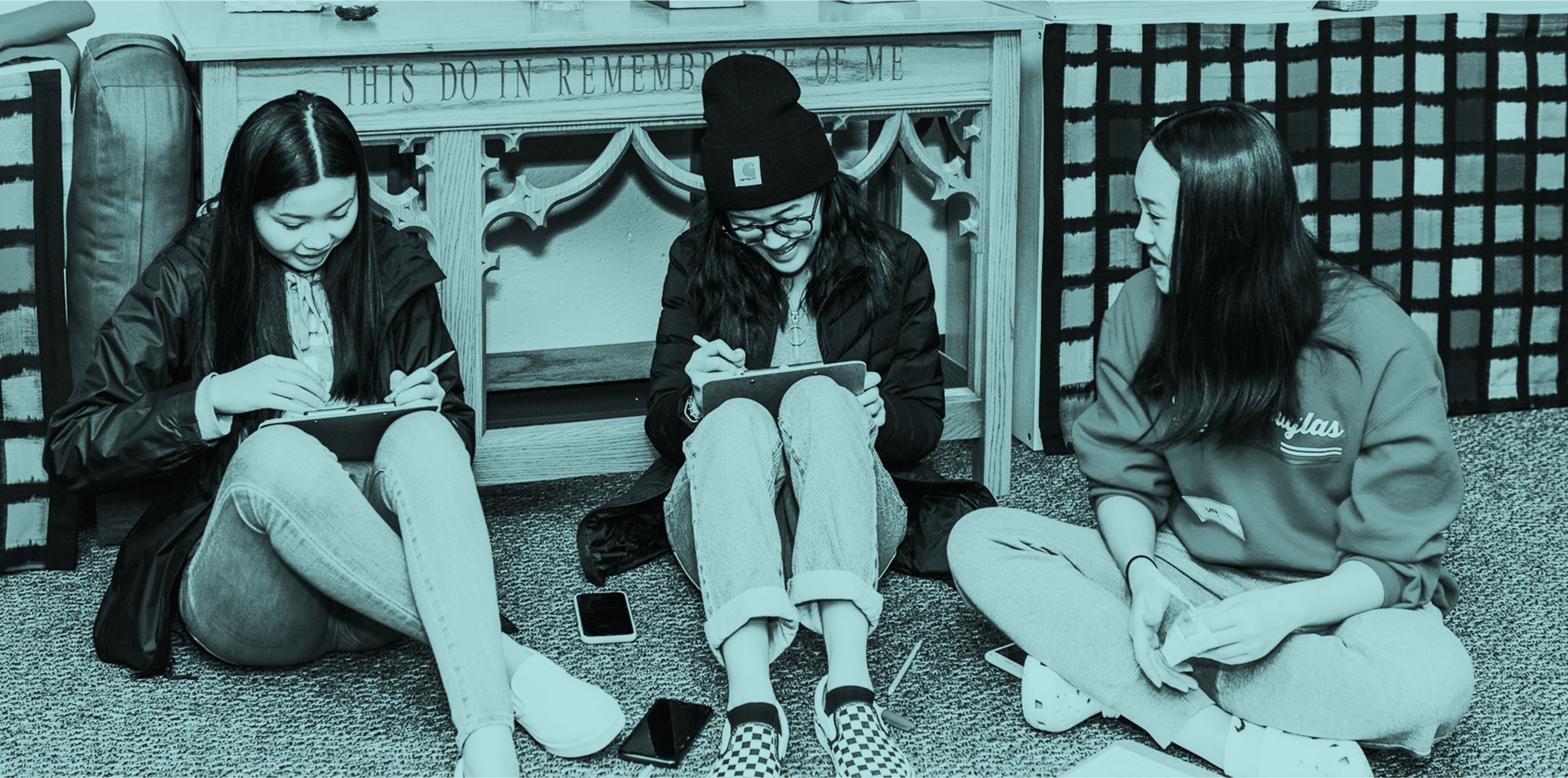 Students sitting on the ground writing on clipboards #0