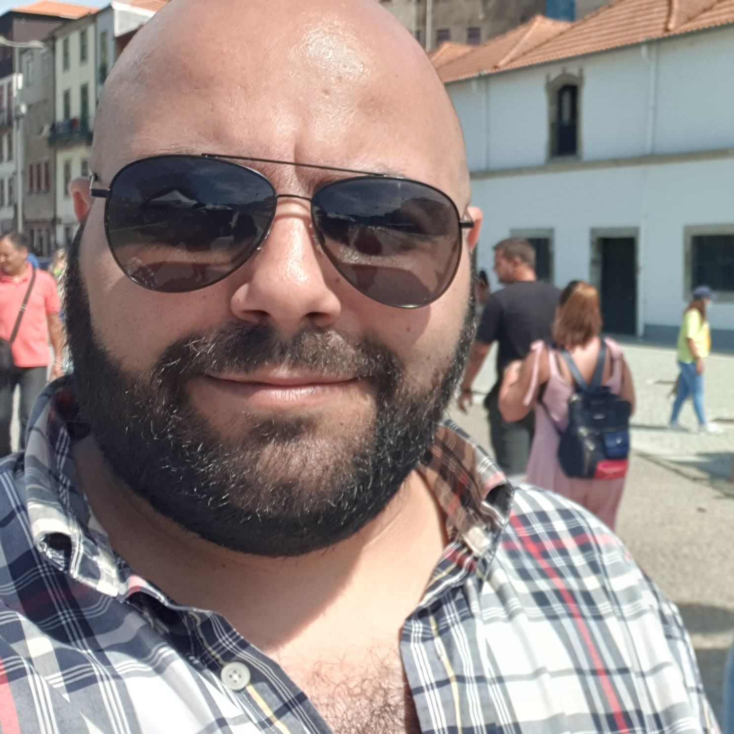 A photograph of Pedro Ferreira wearing sunglasses and smiling, set against a backdrop of Porto, in Portugal