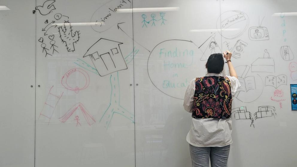 Image of a student writing on a white board