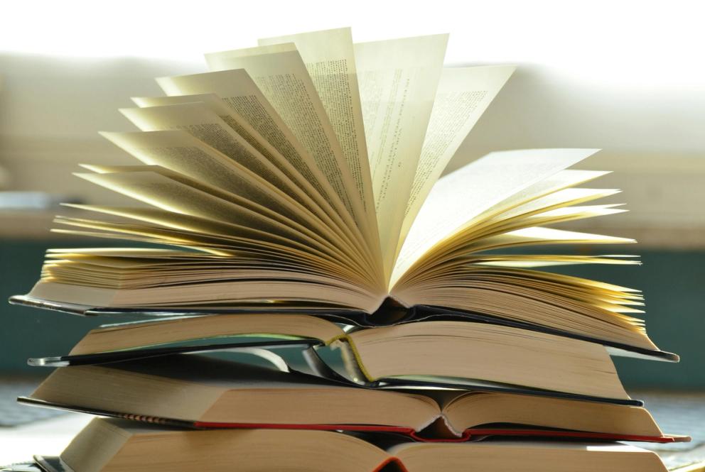 An image of a pile of books, with the top book open
