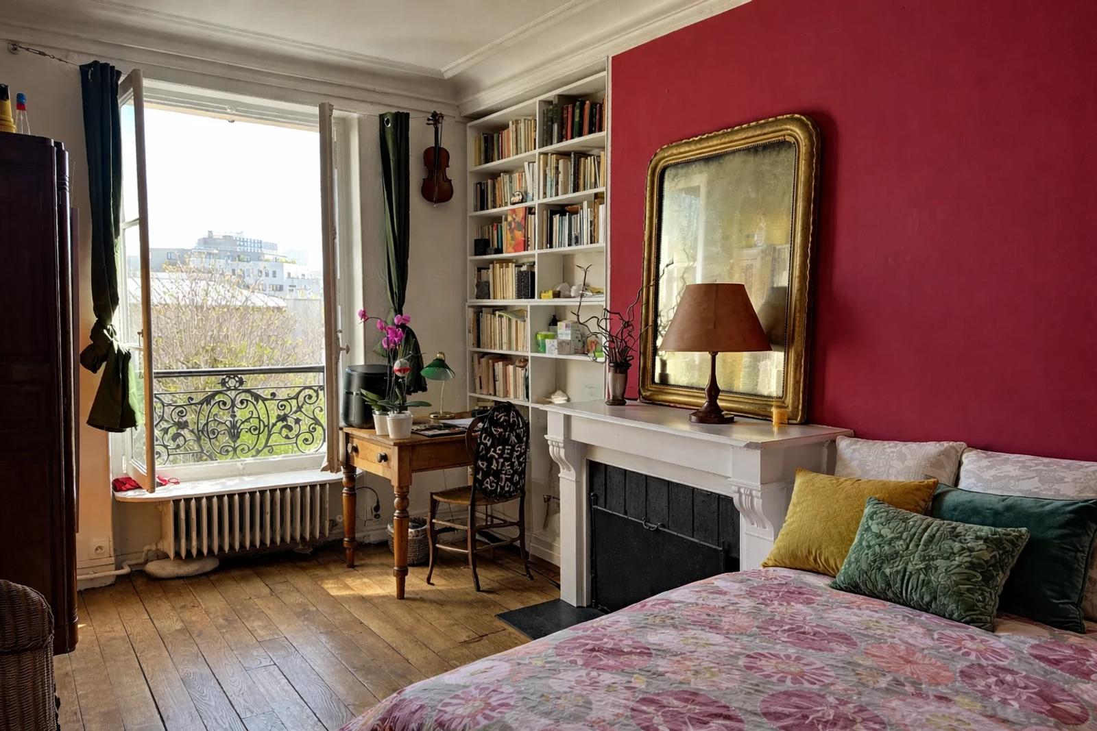 Pièce avec cheminée, bibliothèque et porte-fenêtre donnant sur un balcon — Paris 14e.