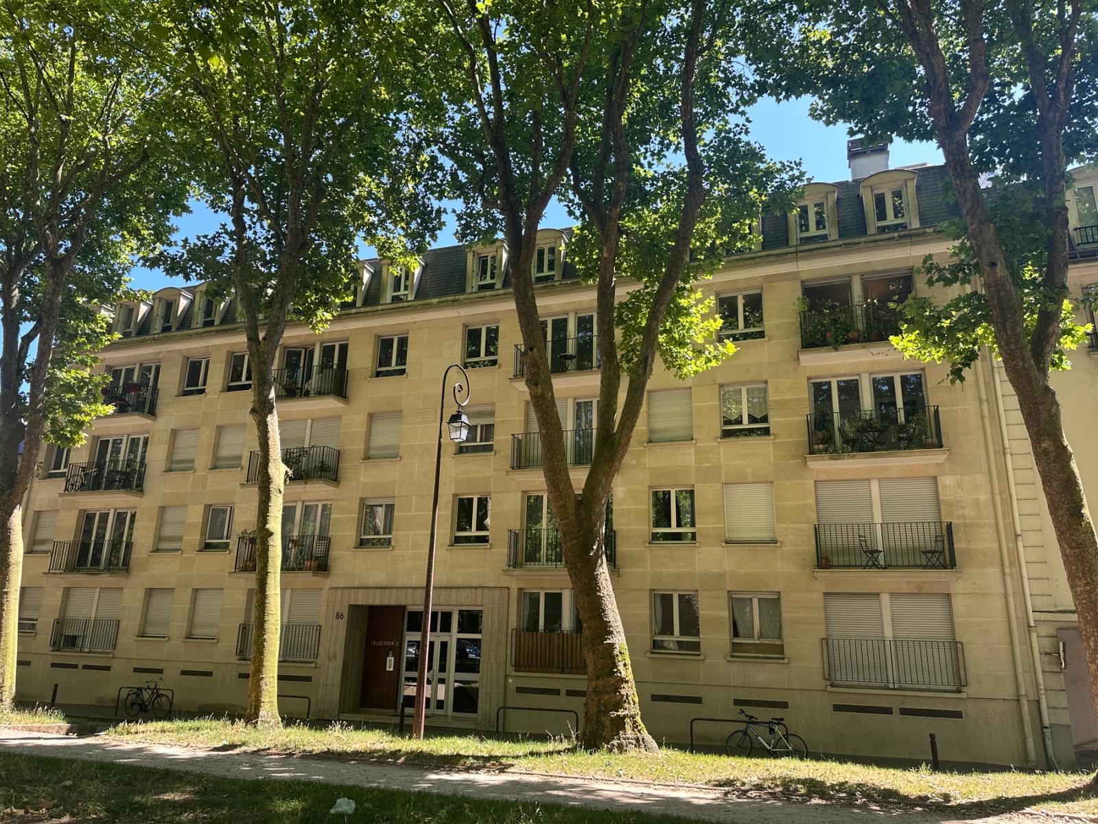 Façade de la résidence bordée de grands arbres — Versailles.