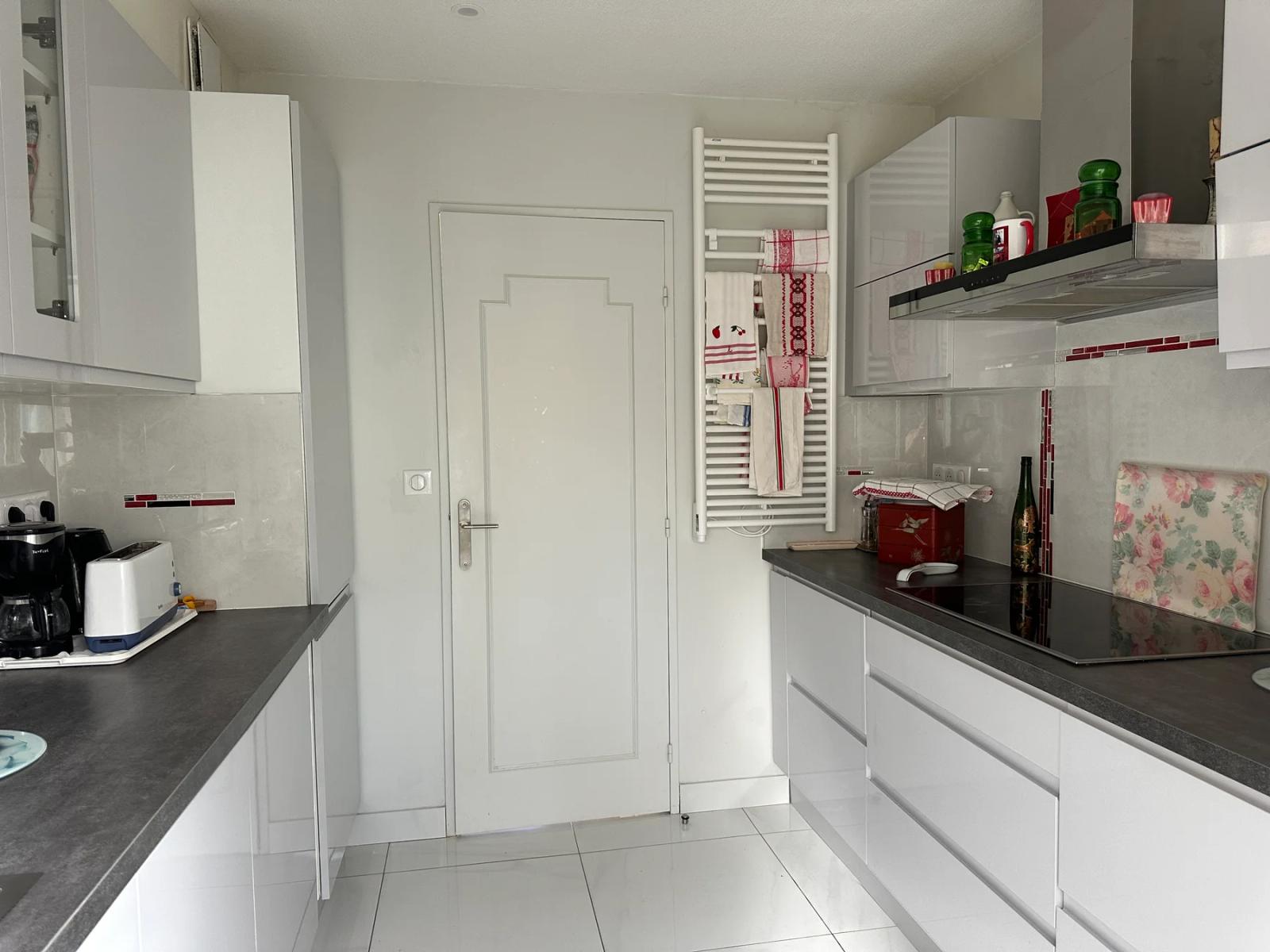 Cuisine avec rangements blancs, plan de travail sombre et sèche-serviettes — Maule.