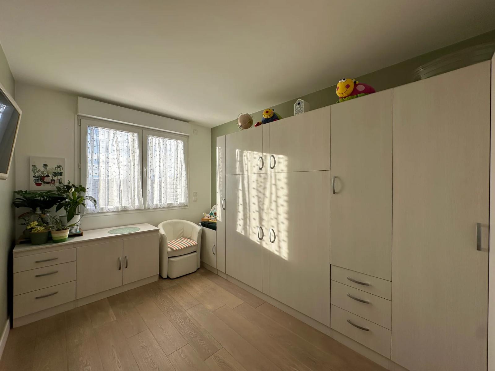 Chambre avec grands rangements blancs et fauteuil près de la fenêtre — Meudon-la-Forêt.