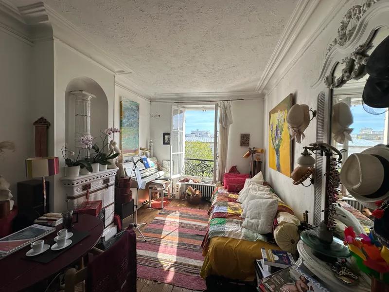 Séjour avec parquet, moulures et fenêtre ouverte sur la verdure — Paris 14e.