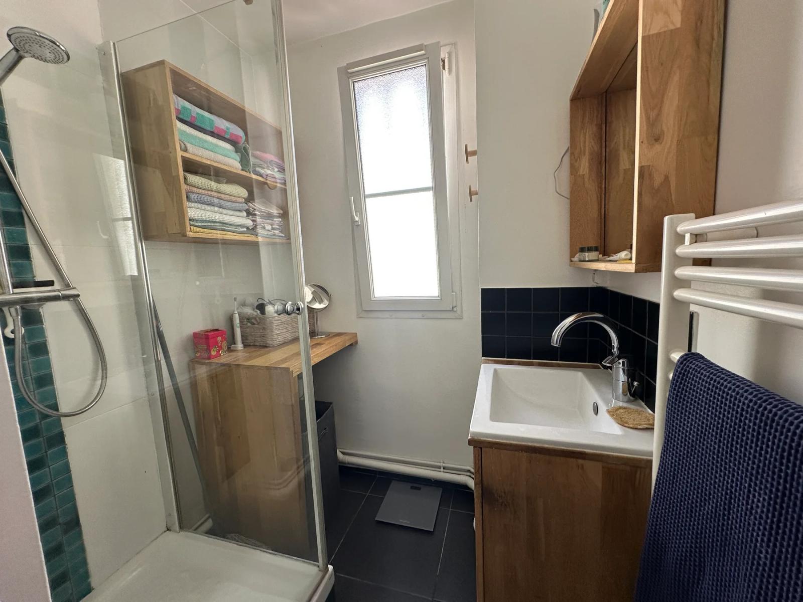 Salle d’eau avec douche vitrée, vasque et fenêtre — Paris 11e.