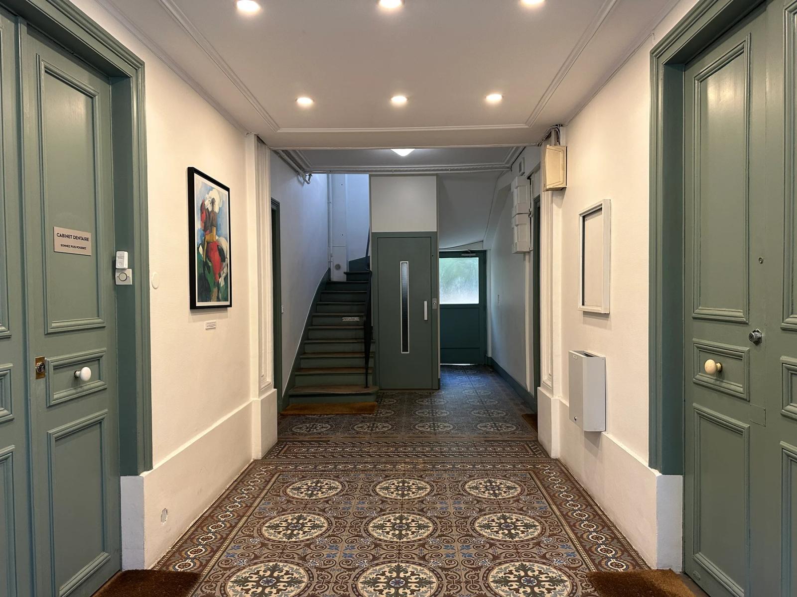 Hall de l’immeuble avec carrelage à motifs et escalier — Paris 14e.