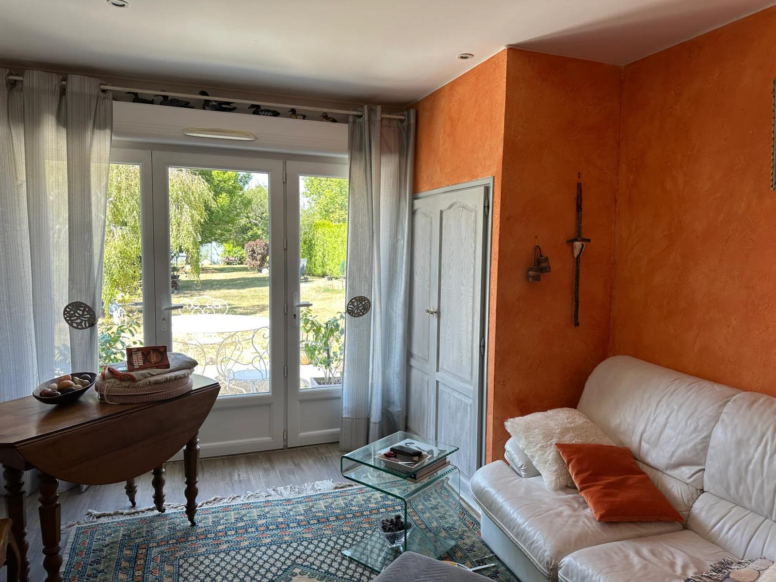 Pièce avec canapé, table et baie vitrée donnant sur le jardin — Maule.