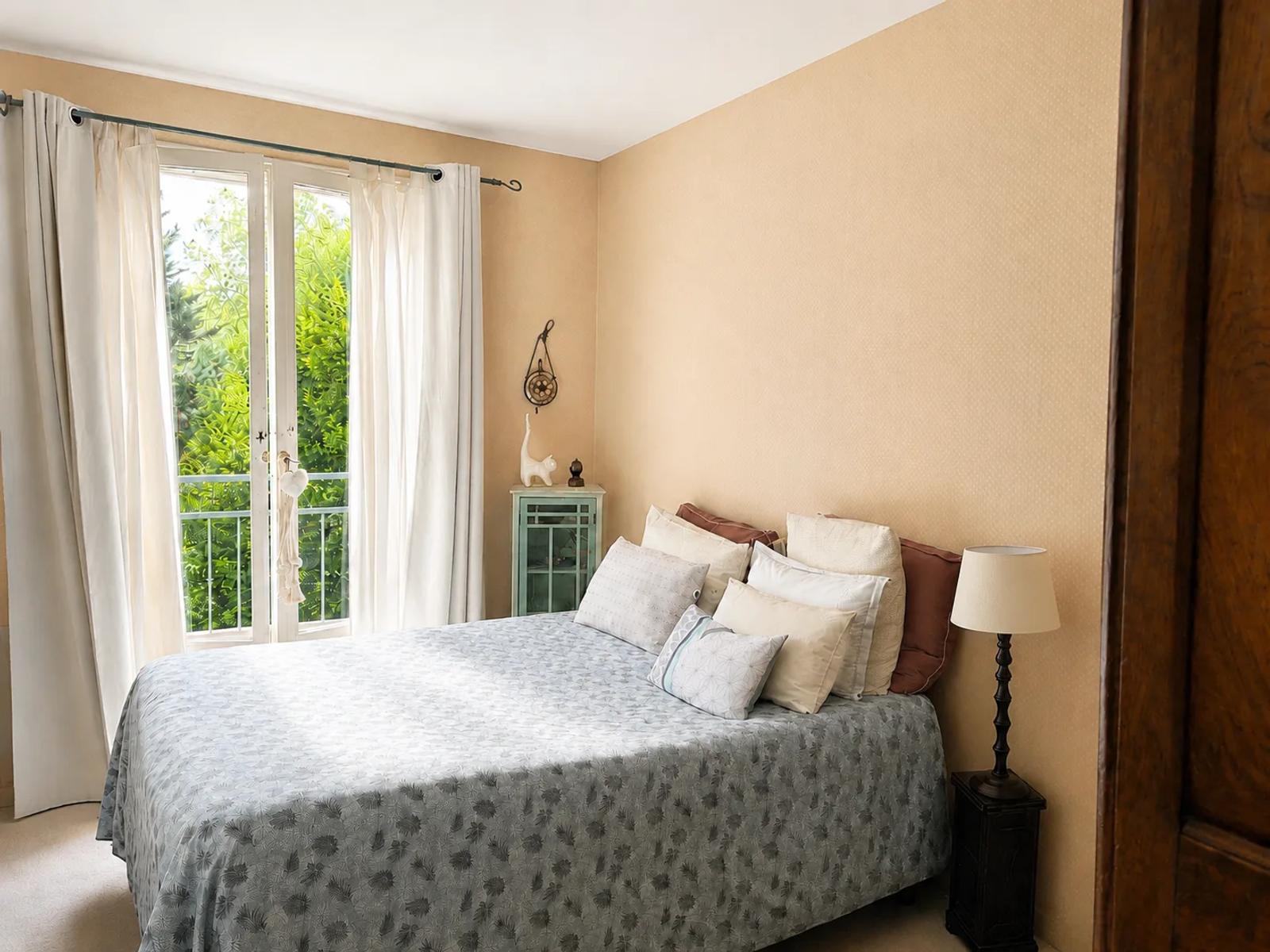 Chambre avec lit double et porte-fenêtre donnant sur la verdure — Versailles.