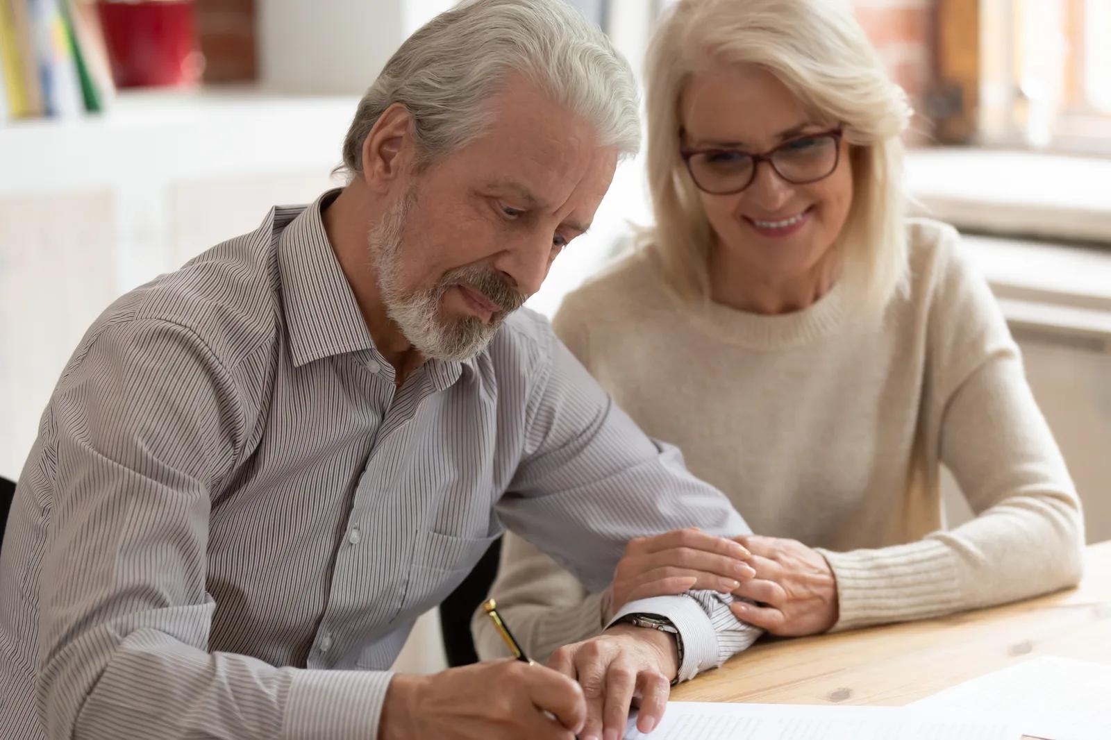 Un couple de seniors consulte des documents ensemble à une table.