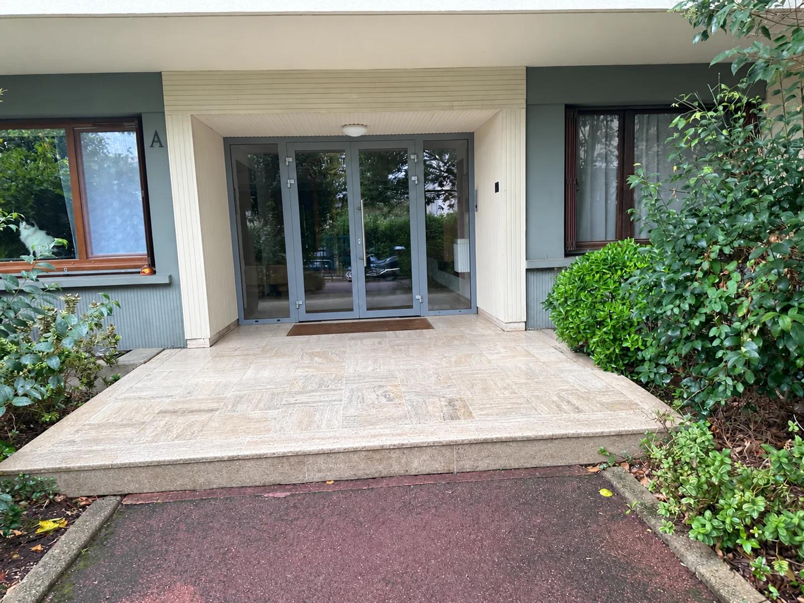 Entrée de l’immeuble bordée de végétation — Carrières-sur-Seine.